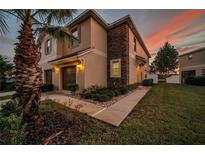 Two-story home featuring a stucco exterior, stone accents, attached garage, and landscaped yard at 12025 Greengate Dr, Hudson, FL 34669