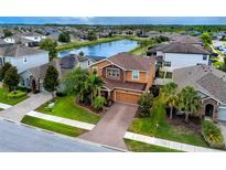 Beautiful two-story home boasts mature landscaping, brick driveway, and serene water views at 1601 Fox Grape Loop, Lutz, FL 33558
