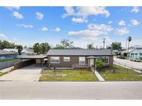 Charming single-story home featuring a carport, fenced yard, and inviting front porch, perfect for enjoying the neighborhood view at 1701 N Tampania Ave, Tampa, FL 33607