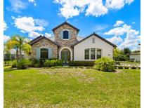 Charming two-story home with a stone facade, arched entryway, blue shutters, and a well-manicured front lawn at 2839 Cordoba Ranch Blvd, Lutz, FL 33559