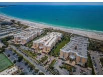 Stunning aerial view of beachfront condo complex with pristine white sands and turquoise ocean waters at 6600 Sunset Way # 118, St Pete Beach, FL 33706