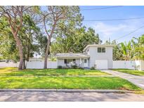 Charming two-story home featuring a manicured lawn, a white fence and a single car garage at 1518 Cheyenne Ne St, St Petersburg, FL 33703