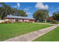 Charming single-story home with manicured lawn, mature trees, and metal roof at 15316 Winding Creek Dr, Tampa, FL 33613