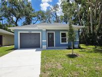 Charming single-story home with a blue exterior, gray garage door, and well-maintained front yard at 1565 S Martin Luther King Jr Ave, Clearwater, FL 33756