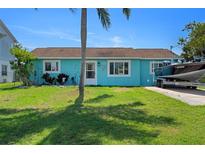 Charming home with a vibrant blue exterior, well-maintained lawn, boat on the driveway, and a palm tree at 3243 Azalea Dr, Hernando Beach, FL 34607