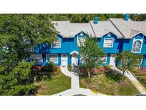 Charming blue townhome with a well-manicured lawn and a welcoming walkway to the front door at 3350 Fox Hunt Dr, Palm Harbor, FL 34683