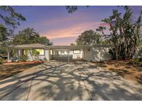Charming single-story home featuring a welcoming covered driveway, lush landscaping, and a beautifully painted exterior at 4925 Alcazar S Way, St Petersburg, FL 33712