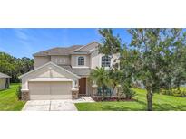 Charming two-story home with landscaped yard, two-car garage, and inviting front porch seating at 5830 100Th E Ave, Parrish, FL 34219