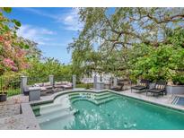 Inviting outdoor pool area with lounge seating, mature trees, and an elegant iron fence at 6220 Bayshore Blvd, Tampa, FL 33611