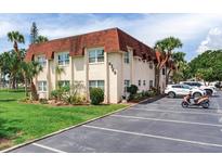 Two-story condo building with red roof, lush landscaping, and ample parking spaces at 6360 1St N St # 202, St Petersburg, FL 33702