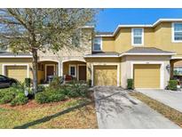 Traditional two-story townhome with attached garages, landscaped yard, and mature shade trees at 6909 Holly Heath Dr, Riverview, FL 33578
