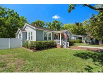 Charming bungalow with tidy lawn, brick pathway, and inviting front porch flying the US flag at 702 W Kentucky Ave, Tampa, FL 33603