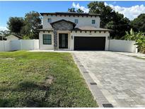 Charming two-story home featuring a stone accent entry, dark garage door and paver driveway at 9005 W Flora St, Tampa, FL 33615