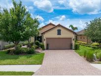 Charming single Gathering home featuring lush landscaping and a brick driveway and a two-car garage at 10450 Highland Park Pl, Palmetto, FL 34221