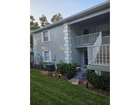 Two-story condominium exterior featuring a small yard and a staircase to the second level entrance at 12133 Spartan Way # 203, Hudson, FL 34667