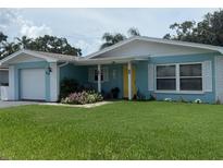 Charming, single-story home with a yellow door and well-manicured front lawn and garden at 1814 Driftwood S Cir, Oldsmar, FL 34677