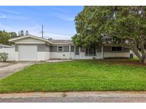 Charming single-story home with a lush green lawn and mature tree shading the front yard at 1848 68Th N Ave, St Petersburg, FL 33702