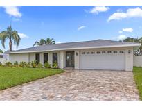 Charming home with a brick driveway, white exterior, and well-maintained landscaping at 1964 Tanglewood Ne Dr, St Petersburg, FL 33702