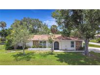 Charming home featuring stone accents, a well-maintained lawn, and an inviting arched front entrance at 20352 Astoria Ave, Port Charlotte, FL 33952