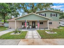 Inviting two-story home with a charming covered front porch, landscaped yard, and an American flag at 205 W Wheeler Rd, Seffner, FL 33584