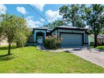Charming single-story home featuring a well-manicured lawn, attached garage, and inviting front entrance at 211 Arlington E Ave, Oldsmar, FL 34677