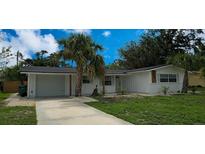 Charming single-story home featuring a driveway, garage, palm trees, and fresh landscaping at 2837 Woodcrest Dr, Sarasota, FL 34239