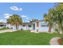 Charming home featuring lush green lawn, palm trees, and freshly painted white exterior at 2837 Woodcrest Dr, Sarasota, FL 34239