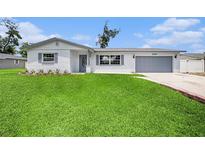 Charming single-story home showcasing a lush green lawn, painted brick exterior, and a gray attached two car garage at 2905 Forest Cir, Seffner, FL 33584