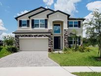 Charming two-story home featuring stone accents, a two-car garage, and a well-manicured lawn at 38120 Shale Stone Ct, Zephyrhills, FL 33540