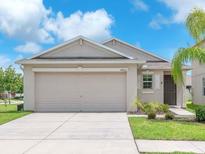 Charming single-story home featuring a two-car garage, neutral paint, and a well-manicured lawn at 4902 Grist Mill Ct, Wimauma, FL 33598