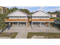 A street-level exterior of this two-story light gray home with a brown roof, concrete driveway and wooden deck at 6602 S Sherrill St, Tampa, FL 33616