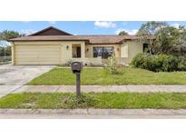 Single-Gathering home featuring an attached one-car garage and a traditional mailbox at 7018 Arbor View Ln, New Port Richey, FL 34653