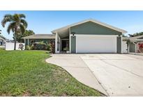 Charming home with a two-car garage, well-maintained lawn, and lush landscaping at 852 Crystal Dr, Palm Harbor, FL 34683
