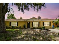Charming single-story home featuring a yellow exterior, black shutters, and landscaped front yard at 1320 Oak Valley Dr, Seffner, FL 33584