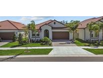 Charming single-story home with a tile roof, well-manicured lawn, and a two-car garage at 17418 Holly Well Ave, Wimauma, FL 33598