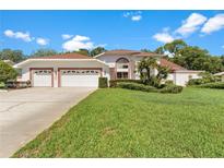 Charming single-Gathering home featuring a well-manicured lawn, three-car garage, and mature landscaping at 18561 Winding Oaks Blvd, Hudson, FL 34667