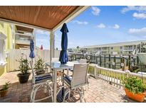 This covered brick patio features waterfront views, with seating for four, under blue umbrellas on a sunny day at 4984 Beach Se Dr # B, St Petersburg, FL 33705