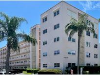 Condominium exterior featuring palm trees and well-maintained landscaping against a backdrop of blue skies at 5623 80Th N St # 406, St Petersburg, FL 33709