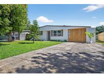 Charming home featuring a modern design, mature trees, a well-manicured lawn, and unique wooden architectural details at 8939 90Th Ave, Seminole, FL 33777
