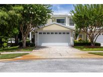 Charming home featuring a two-car garage, lush landscaping, and a welcoming entrance, offering curb appeal and convenience at 932 Woodbridge Ct, Safety Harbor, FL 34695