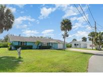 Charming light blue home with a well-manicured lawn and mature palm trees, offering curb appeal at 105 E North Branch Rd, Ruskin, FL 33570