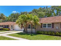 Charming home featuring a stone facade, well-maintained lawn, mature landscaping, and a lovely tile roof at 1102 Cara Dr, Largo, FL 33771