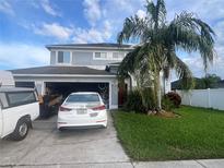 Two-story home with a blue exterior, mature landscaping, an open garage, and a white car parked in the driveway at 1521 Atami Ct, Wesley Chapel, FL 33544