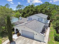 Two-story home featuring an attached garage with a light gray door and a well-maintained landscaped yard at 15722 Gardenside Ln, Tampa, FL 33624