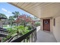 Inviting condo entryway featuring a decorated door and peaceful views of well-maintained landscaping at 2681 Sabal Springs Cir # 204, Clearwater, FL 33761