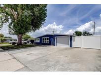 Blue single-story home with a white garage door, fence, and a well-maintained driveway at 4727 Town N Country Blvd, Tampa, FL 33615