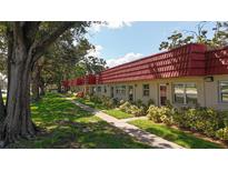 Charming condos with red roofs line a sidewalk through a well-maintained lawn and mature trees at 5870 38Th N Ave # 44, St Petersburg, FL 33710