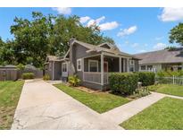 Charming single-story home with a gray exterior, inviting front porch and well manicured lawn at 6016 N Dexter Ave, Tampa, FL 33604