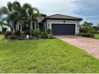 Charming single-story home featuring a tile roof, well-manicured lawn, and a brick driveway at 7683 Summerland Cv, Lakewood Ranch, FL 34202