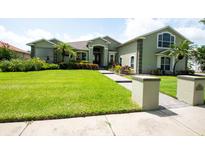 Well-manicured front yard of a charming green home, featuring lush lawn and colorful landscaping at 916 Bunker View Dr, Apollo Beach, FL 33572
